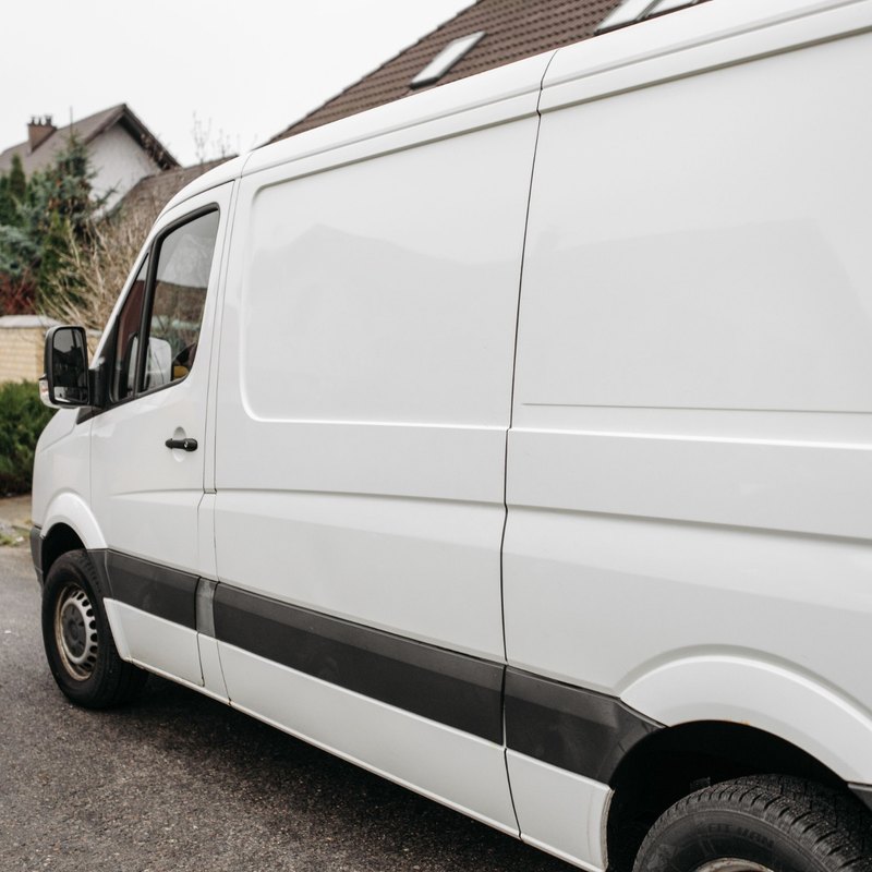 Side of a white delivery van parked on a residential street