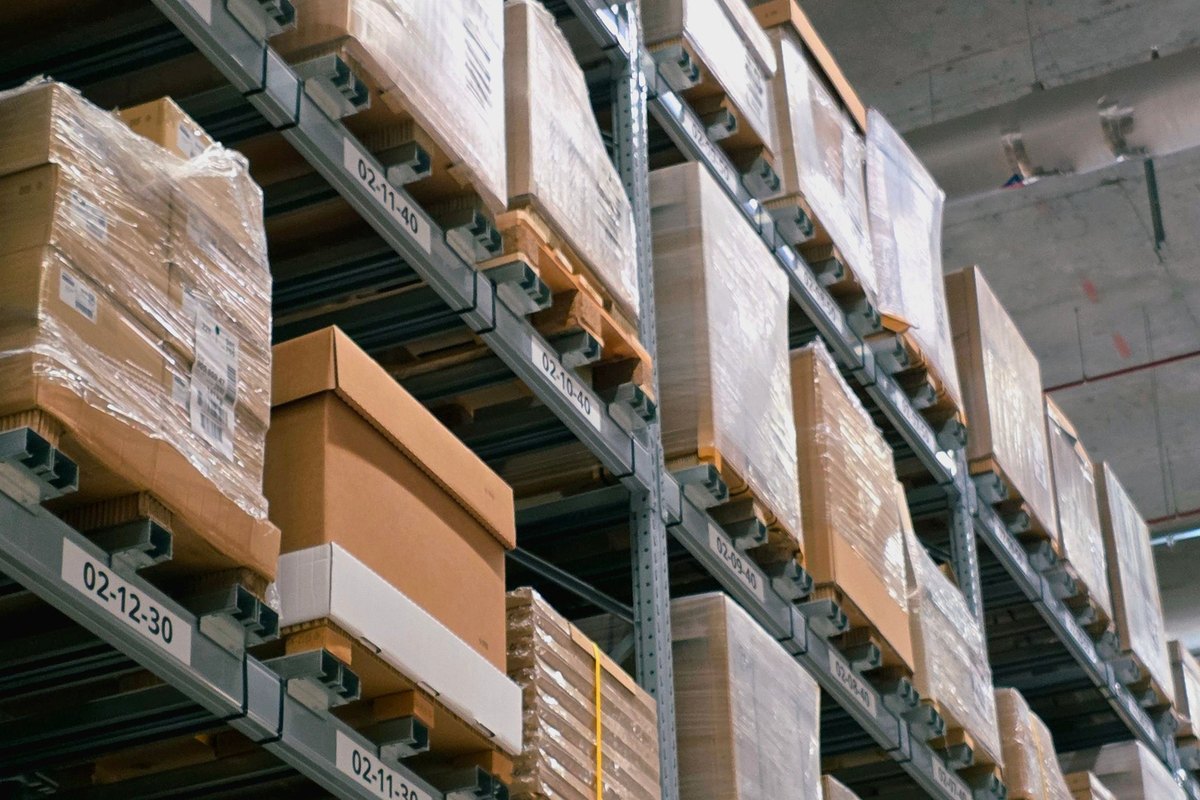 Shrink-wrapped pallets of boxes stacked on tall warehouse racking