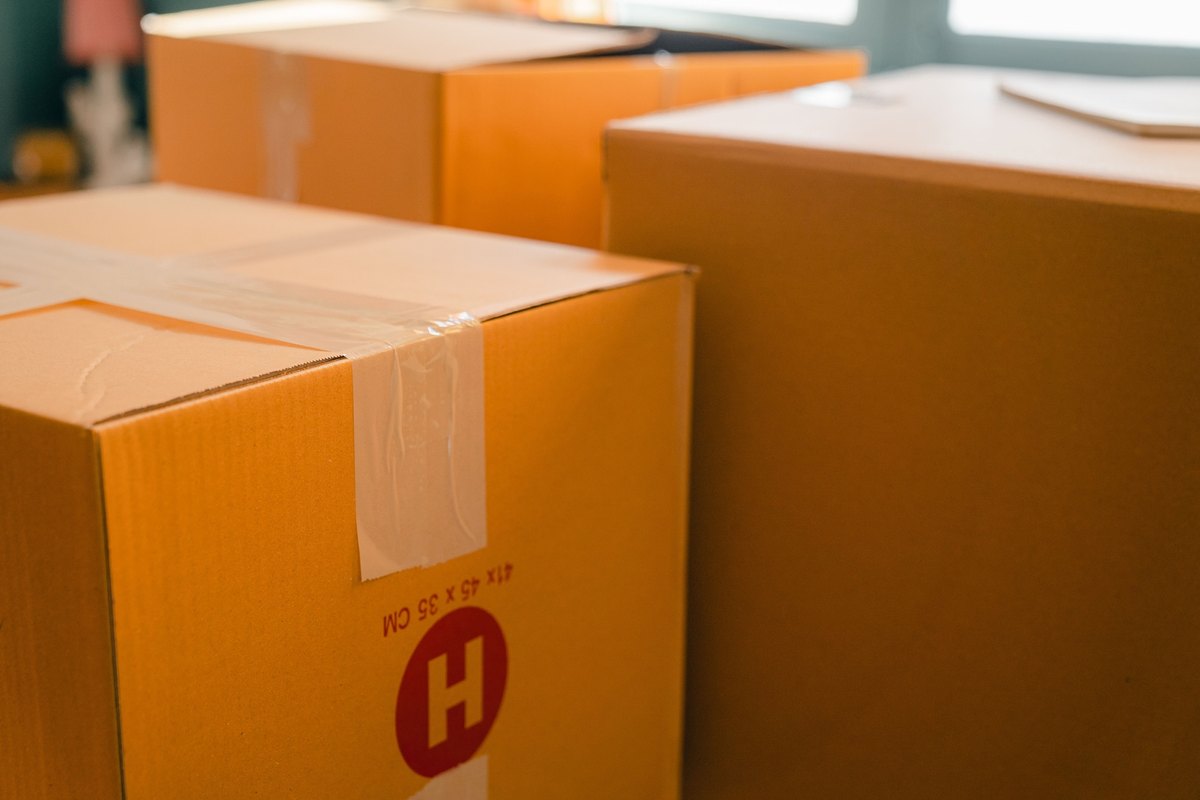Large taped cardboard boxes in a room with a window behind