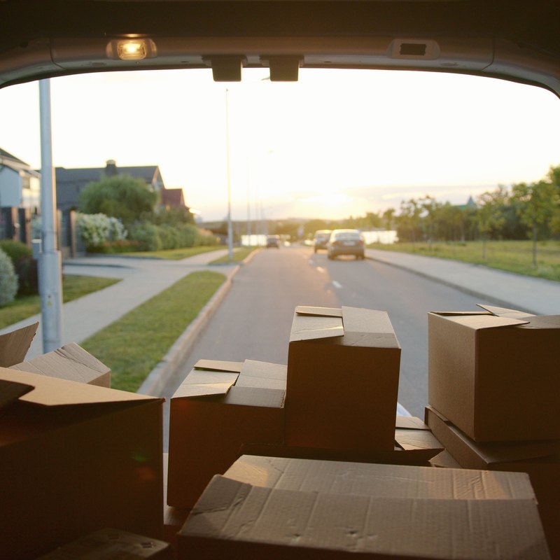 View out the back of a delivery van loaded with boxes onto a quiet residential street at sunset