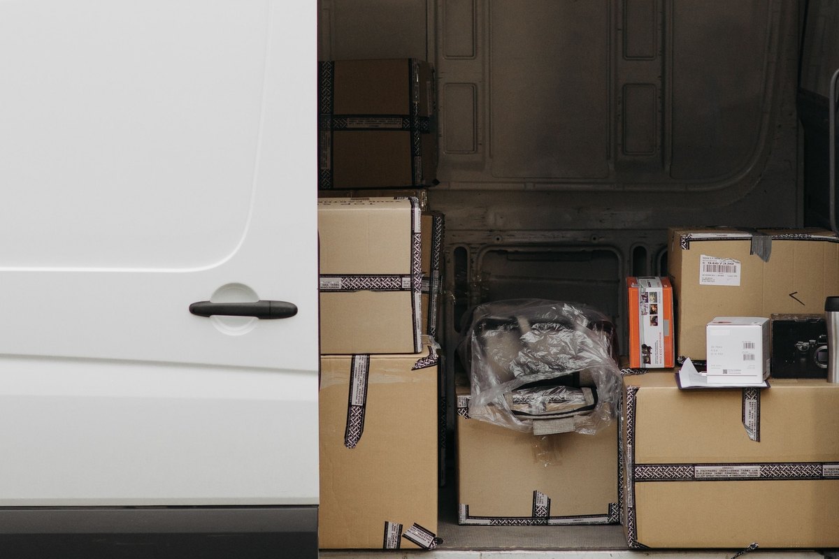 White delivery van with its side door open showing stacked cardboard boxes