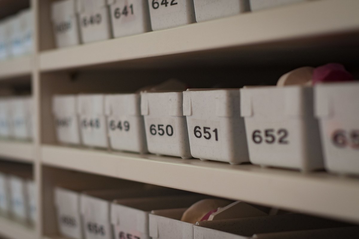 Rows of numbered white plastic storage bins on beige shelves