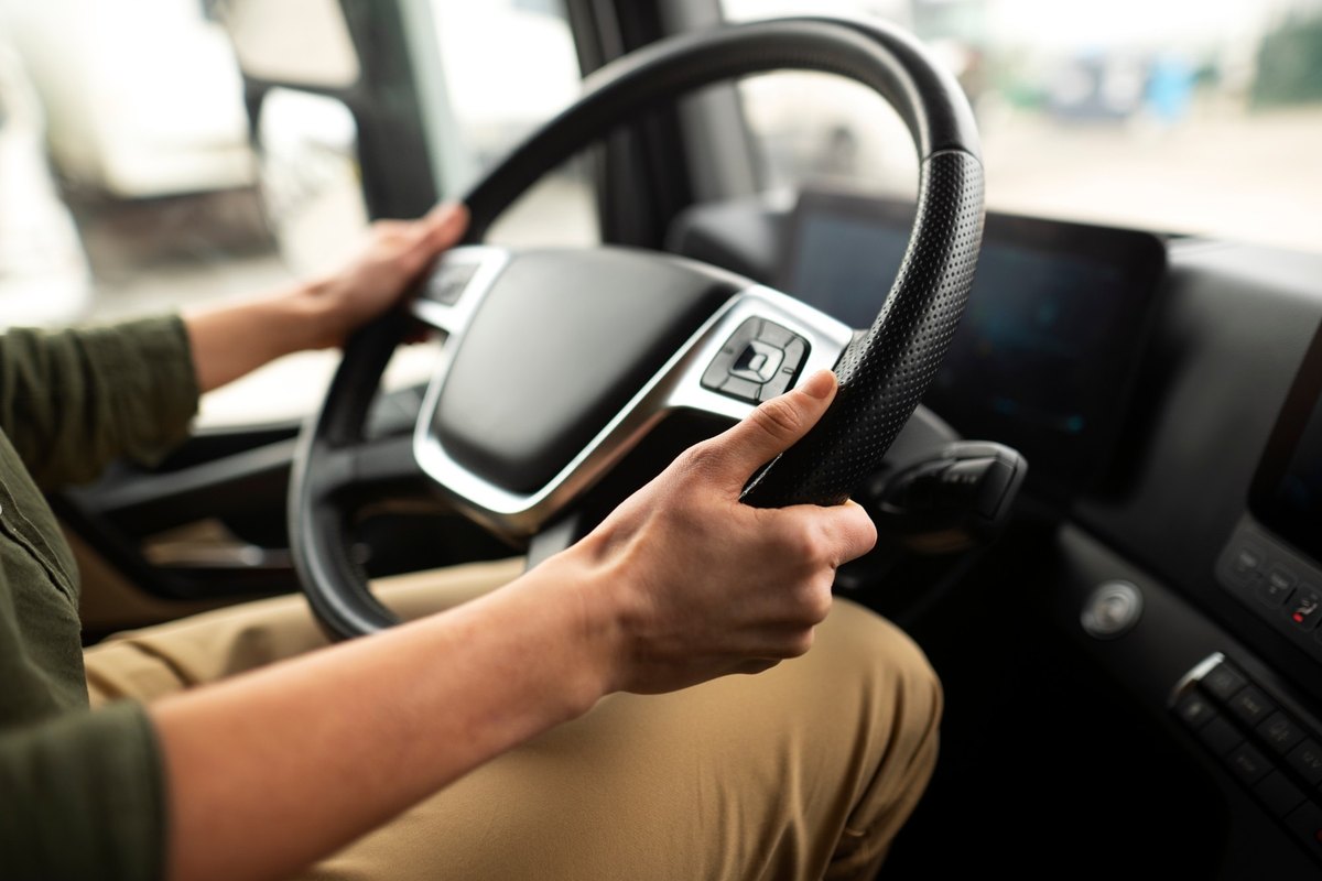 Driver's hands on the steering wheel inside a truck cab